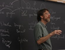 professor Craig Williamson stands in front of a blackboard
